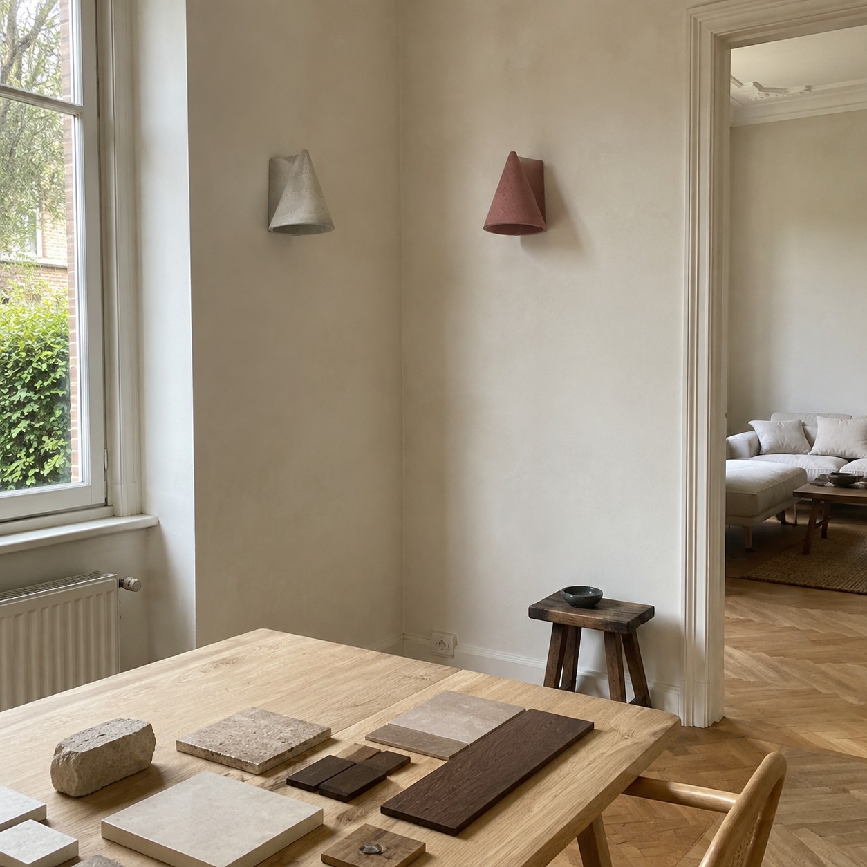 Grijze en baksteenrode betonnen wandlampen tentoongesteld in een rustig, materiaalgericht interieur.