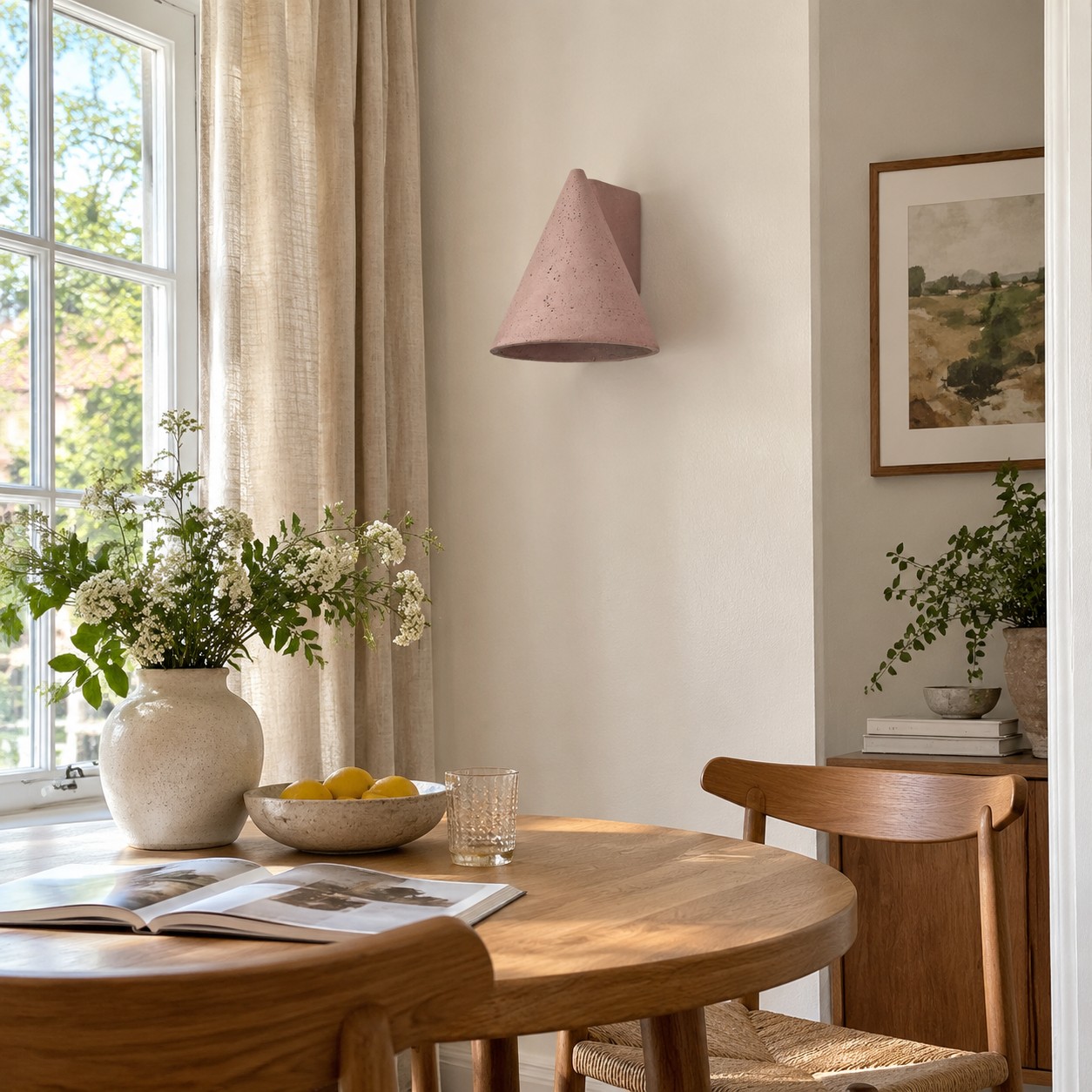Een enkele, sculpturale wandlamp die een ingetogen eethoek in het daglicht verlicht.
