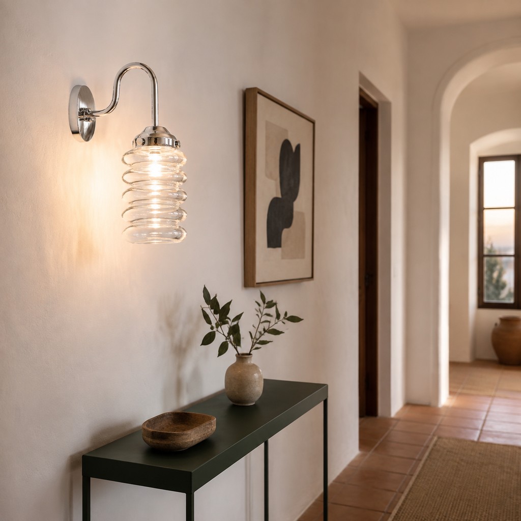 Aplique de pared cromado de cristal estriado transparente junto a un espejo de baño arqueado.