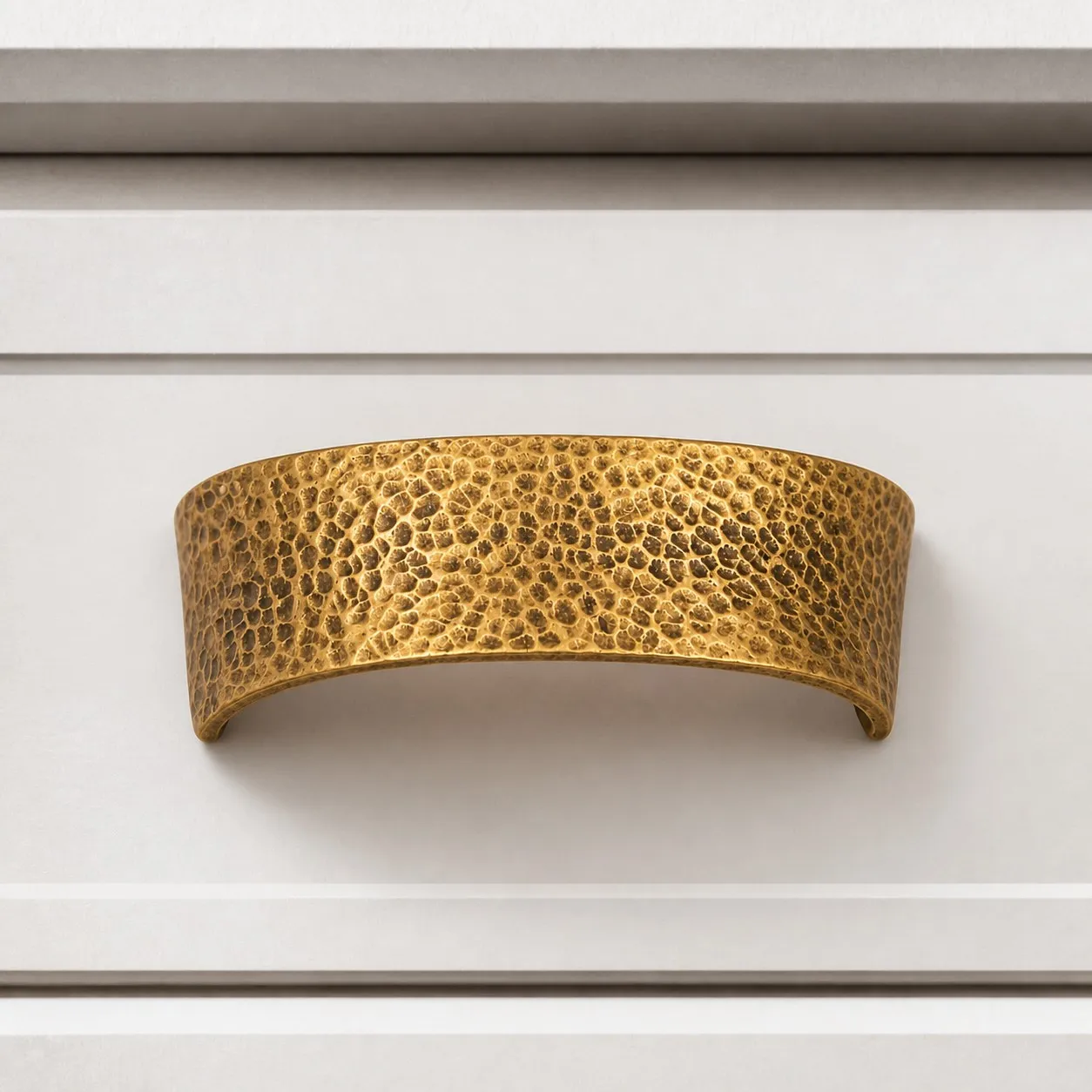Hammered brass cabinet pull on white drawer front